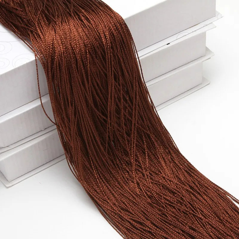 A long, reddish-brown beaded thread curtain hanging down against a white surface.
