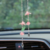 A pink lotus car pendant featuring delicate floral elements and a clear drop.