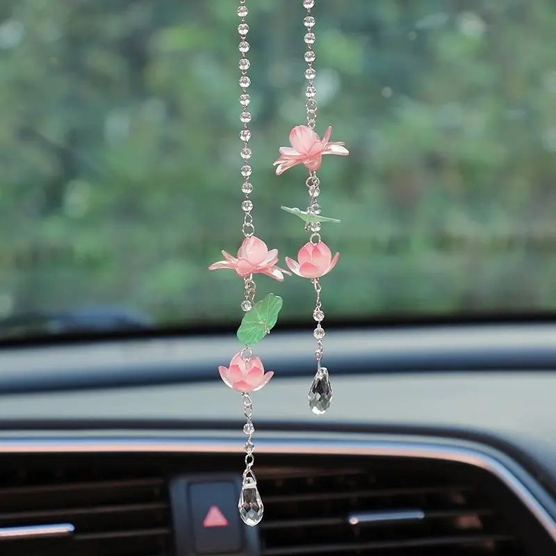 A pink lotus car pendant featuring delicate floral elements and a clear drop.