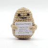 A handcrafted potato plush toy with a muppet face, made of light brown yarn.