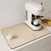 A white espresso machine sits on a beige counter mat with concentric circles, next to some bread.