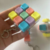 A hand holds a clear plastic container filled with colorful silicone tactile clicking keyboard fidget toys.