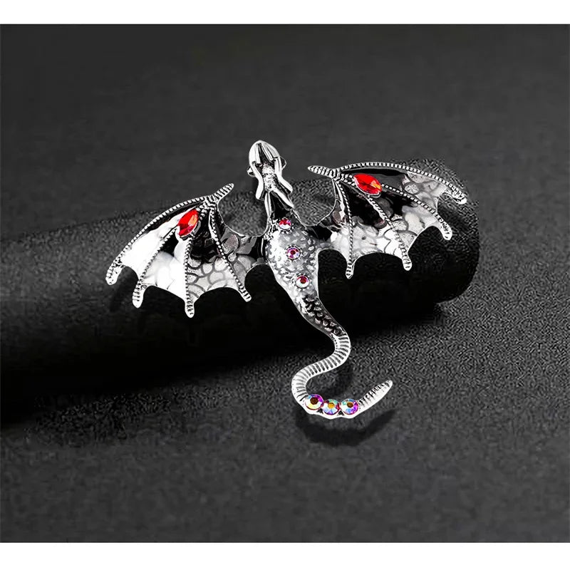 Silver enamel dragon brooch with rhinestone accents displayed on a dark background.
