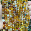 A close-up of a strand of natural square faceted beads in various shades of amber, brown, and green stones for jewelry making