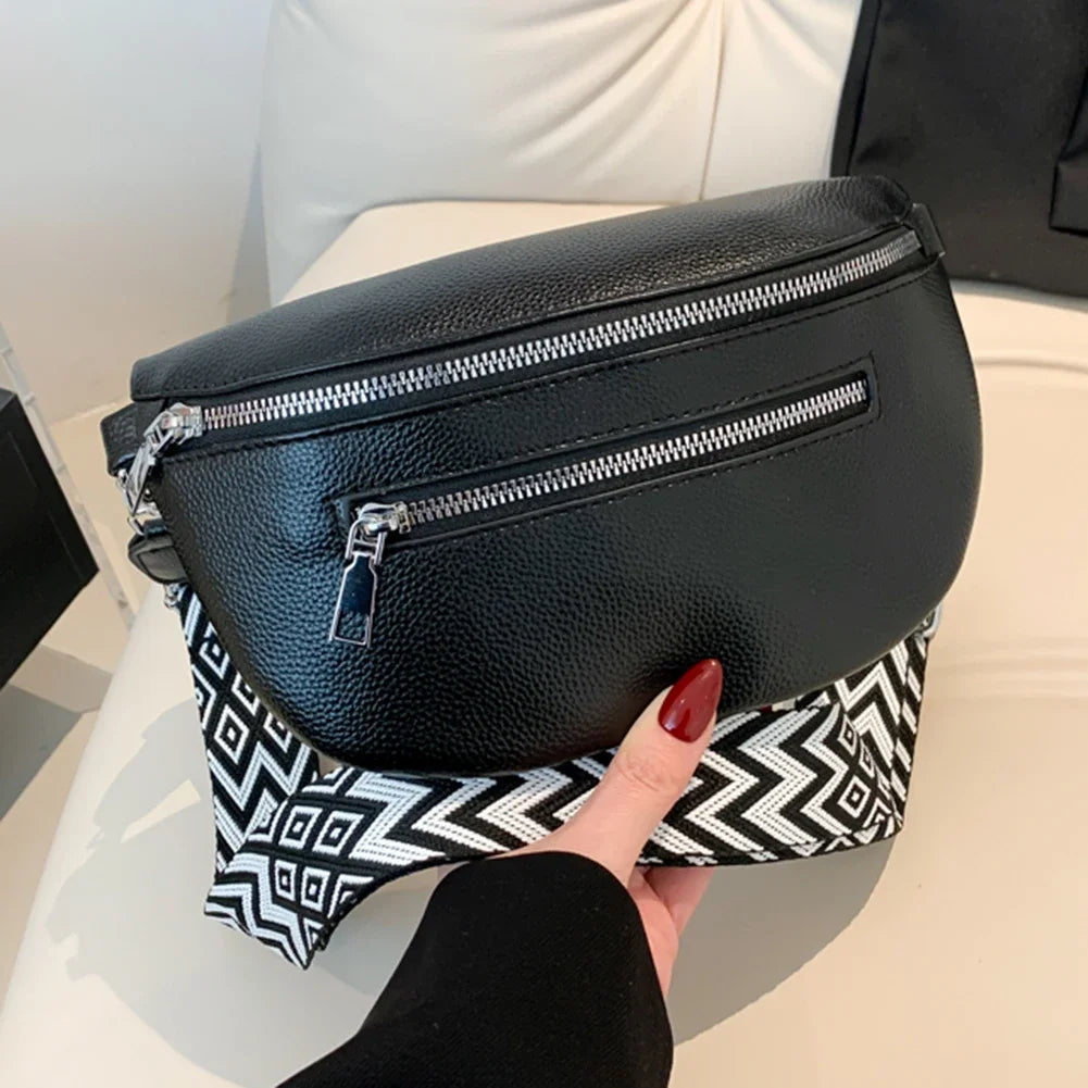 A black multi-pocket PU leather waist bag with a silver zipper is held by a hand against a white surface.