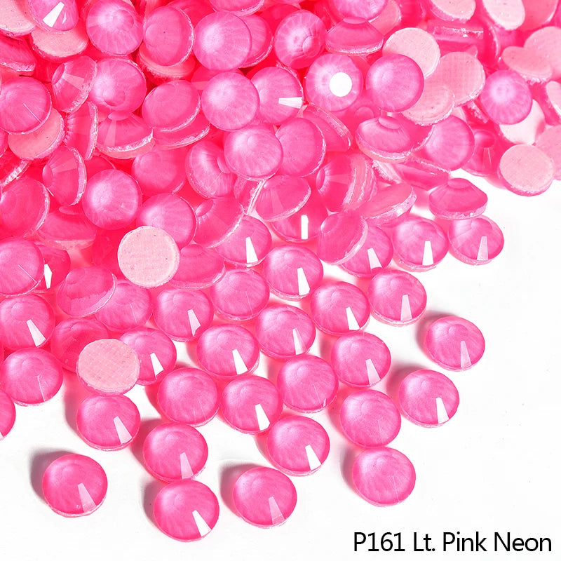 Pink neon rhinestones scattered on a white background for DIY crafts and clothing decoration