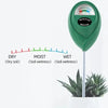 A green soil moisture meter with a needle indicating wetness, placed next to a plant.
