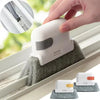 A hand is using a white multi-purpose crevice cleaning brush to clean window tracks and tight spaces.