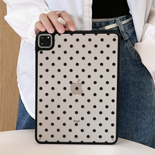 A black polka dot protective case for an iPad is held by a person wearing a white shirt and denim jeans.