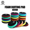 A stack of various foam buffing pads in different colors including black, green, yellow, purple, and orange.