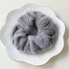 A gray plush coil hair tie resting on a white plate.