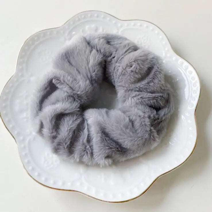 A gray plush coil hair tie resting on a white plate.