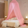 A pink ceiling-hung dome mosquito net draped over a bed in a light-colored room.