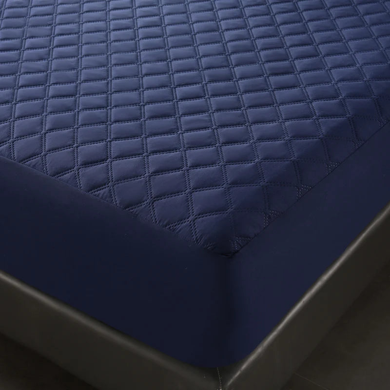 A close-up view of a dark blue quilted waterproof mattress protector with deep pockets.