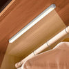 A long, white LED light bar is mounted on a wooden ceiling, illuminating a beige fabric surface.