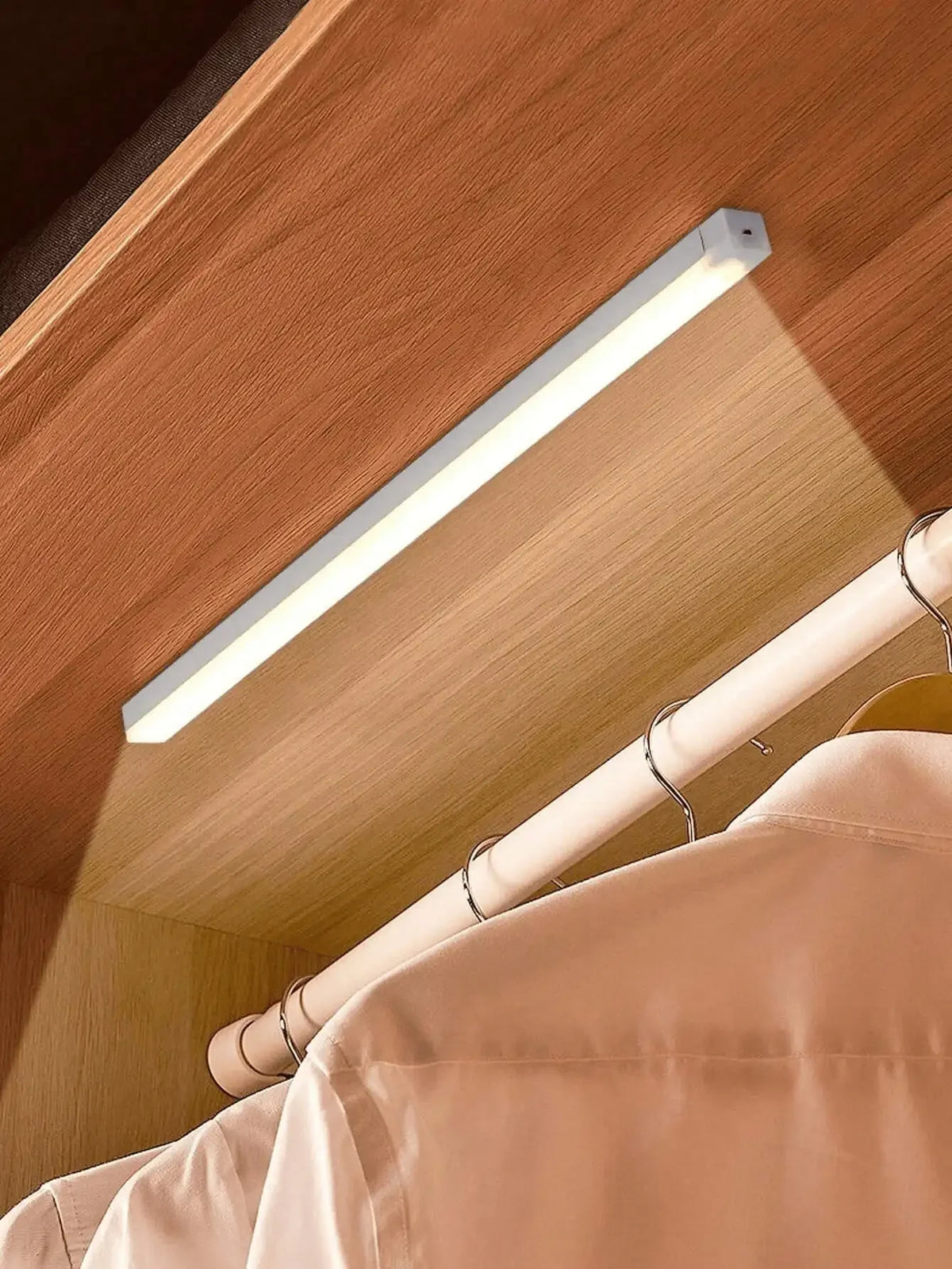 A long, white LED light bar is mounted on a wooden ceiling, illuminating a beige fabric surface.
