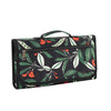 A black foldable waterproof baby changing pad featuring a tropical leaf and fruit pattern.
