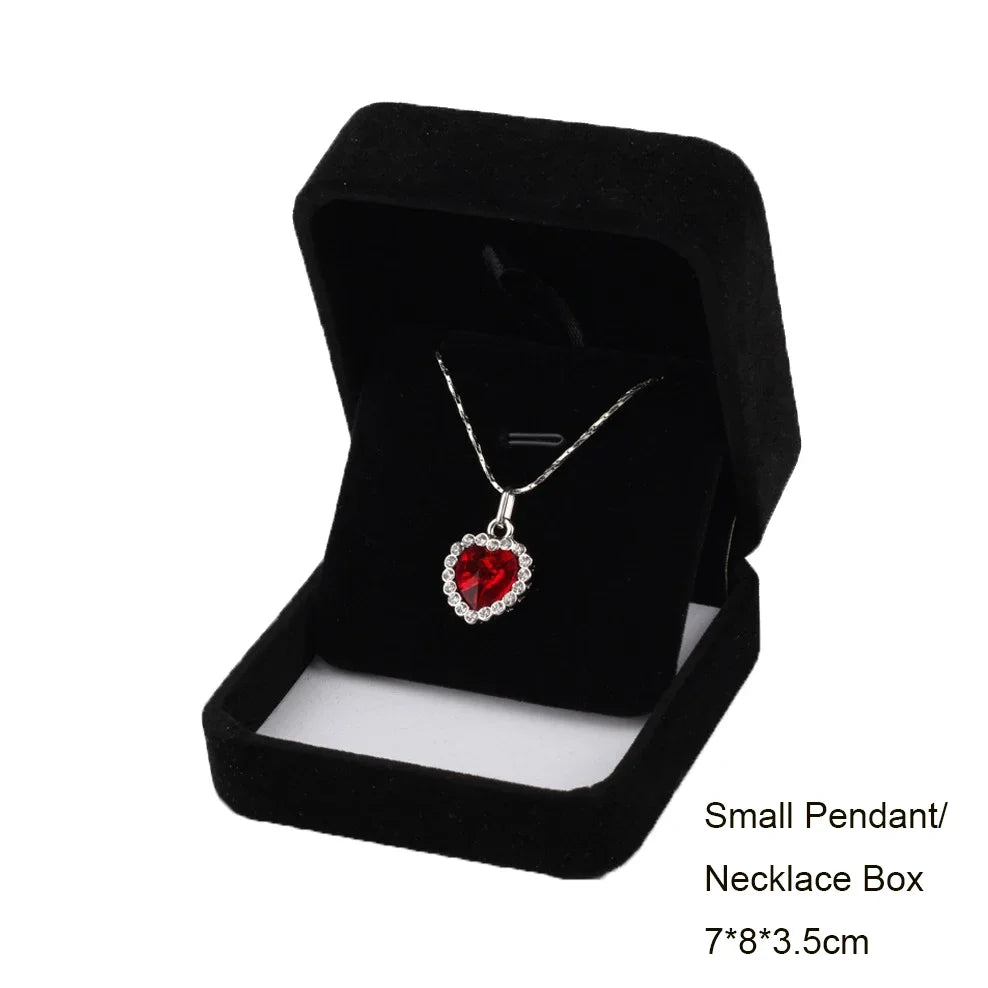 A black velvet box containing a silver heart-shaped pendant necklace.