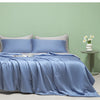 Light blue ice silk summer quilt draped on a bed against a pale green wall.