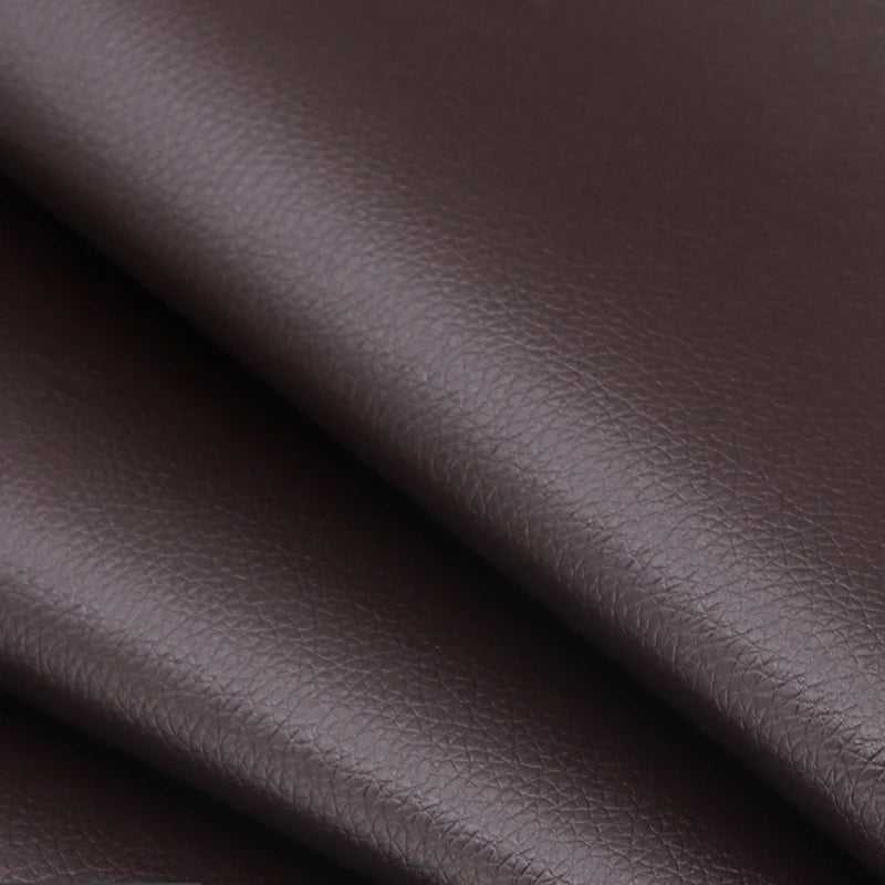 Close-up of dark brown self-adhesive PU leather repair patches being applied to a material.