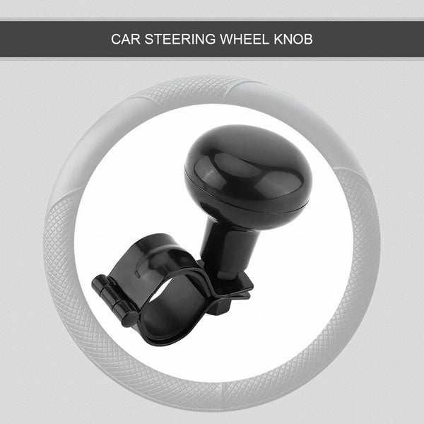 A close-up view of a black car steering wheel knob with a rubber grip, used as a one-hand driving aid.