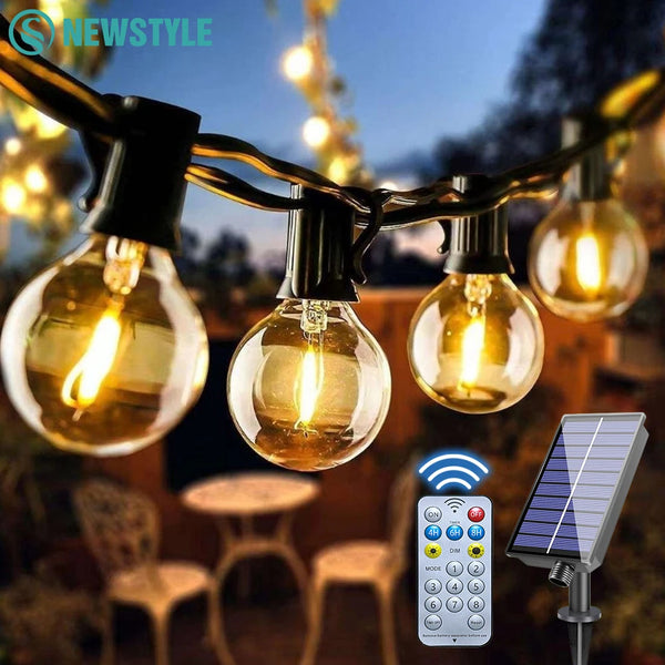 String lights with visible bulbs hanging outdoors, connected to a remote control and solar panel.