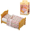 A yellow wooden bed frame with a pink and green patterned bedding set and an accompanying box.