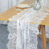 Vintage white embroidered floral lace table runner draped over a wooden table.