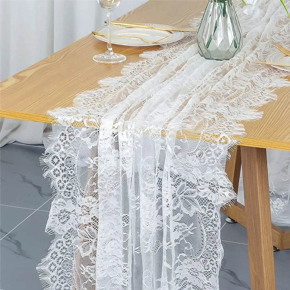 Vintage white embroidered floral lace table runner draped over a wooden table.