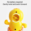 A yellow wind-up bath toy duck is held in a hand, ready for swimming.