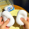 A hand holds a white squishy stress relief fidget ball against a yellow plate.