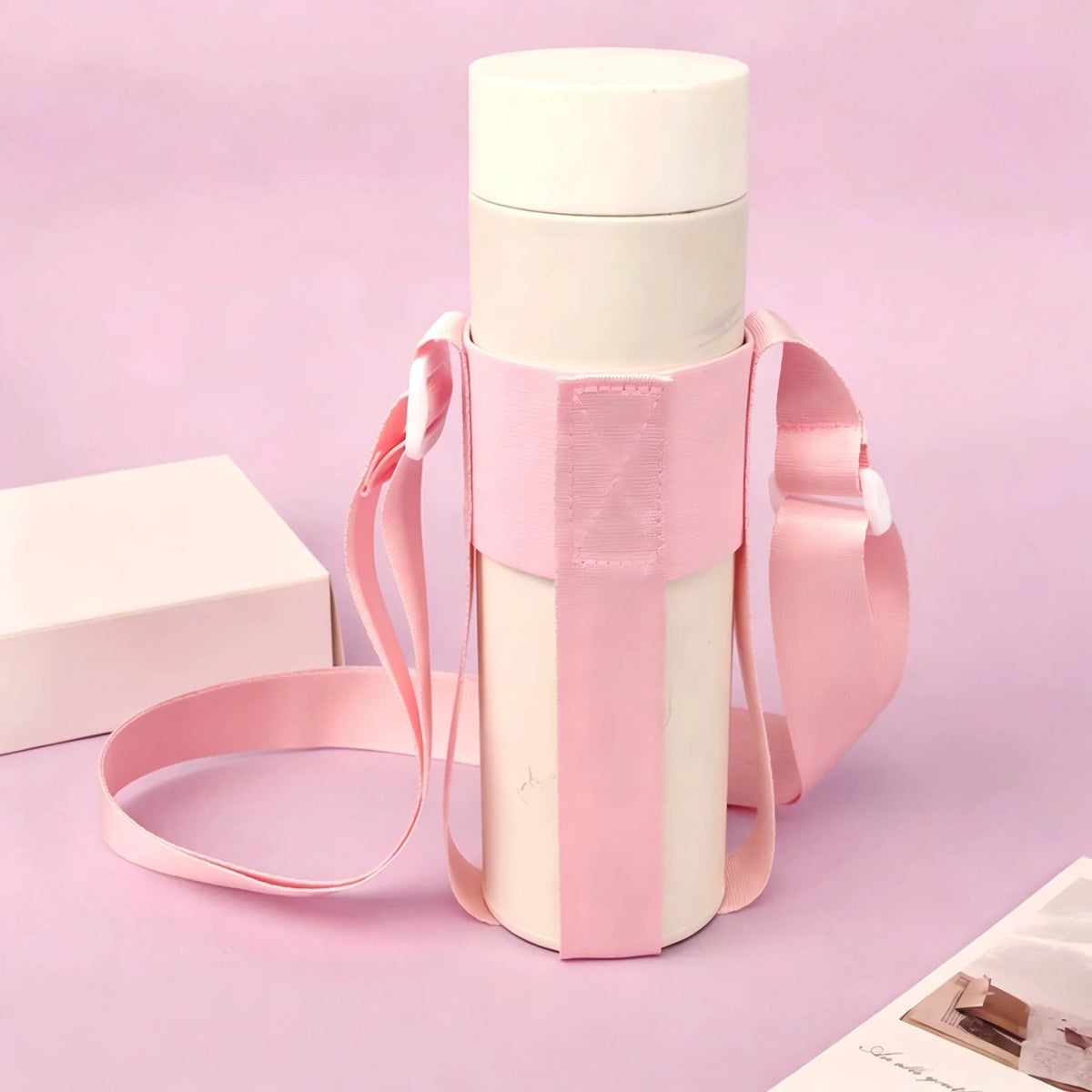 A pink breathable mesh crossbody water bottle carrier with a white bottle and box in the background.