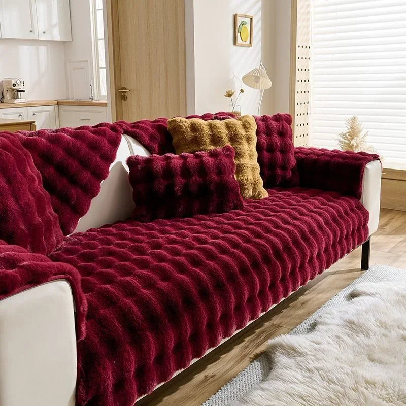 Ein tiefrotes Plüschhase-Sofa-Kissen über einem weißen Sofa, mit einem flauschigen weißen Teppich in der Nähe.