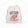 A beige drawstring storage bag featuring text that reads Just a girl who loves capybaras and an illustration of a capybara.