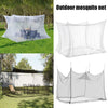 A white mesh mosquito net canopy is shown spread out over a wooden table in an outdoor setting.