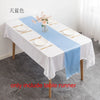 A white tablecloth set with a light blue satin table runner, white plates, and floral centerpiece.