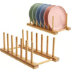 A wooden bamboo dish drying rack holding a stack of five pastel colored plates.