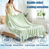 A woman is draped in a light green double-sided cooling silk blanket on a bed, highlighting its skin-friendly and breathable 