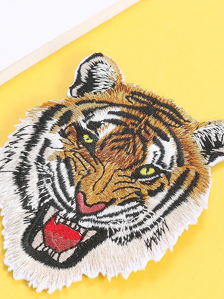 A detailed embroidery patch depicting a tiger's face in orange and black stripes on a yellow background.