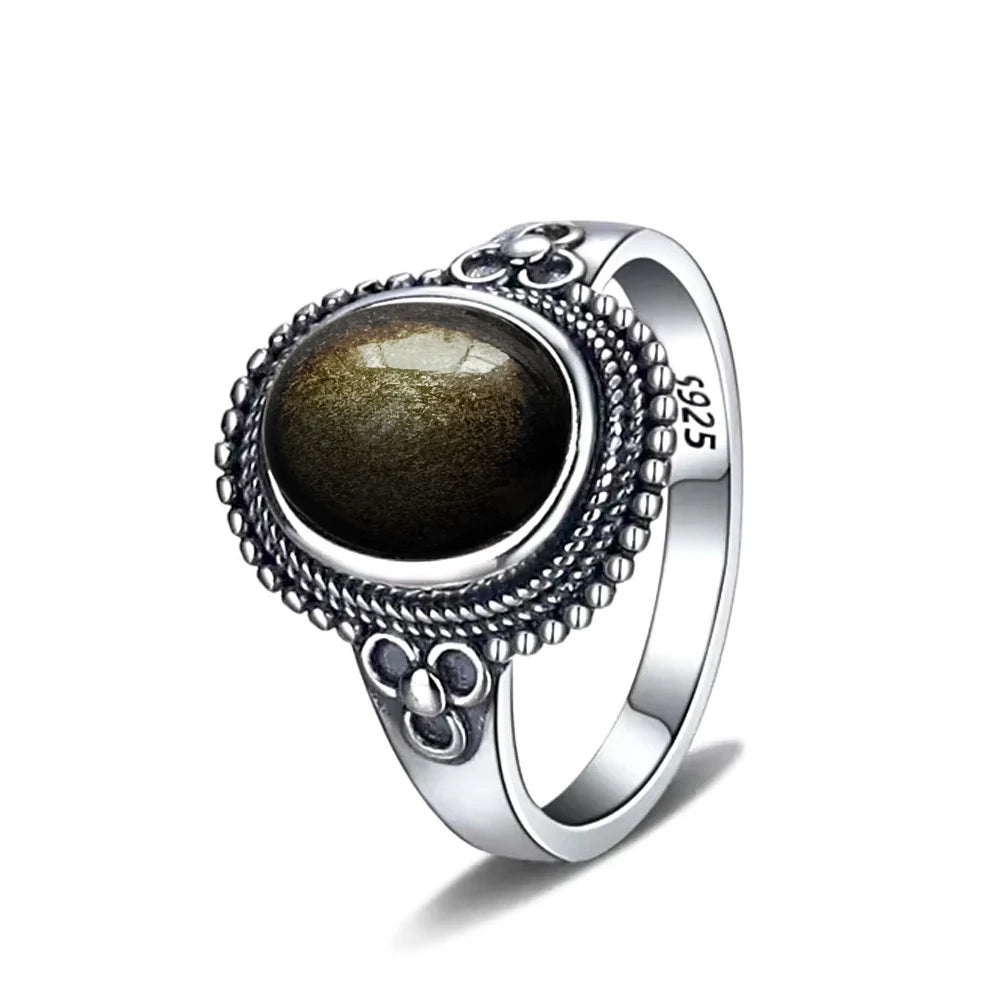 A vintage sterling silver ring featuring an obsidian cabochon set within a sun and flower motif design.