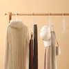 A wooden hanger displays a beige knitted sweater, a white cap, and various fabric items hanging from a multi-layered organize