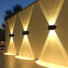 A solar powered LED wall light illuminates a textured wall with upward and downward beams at dusk.