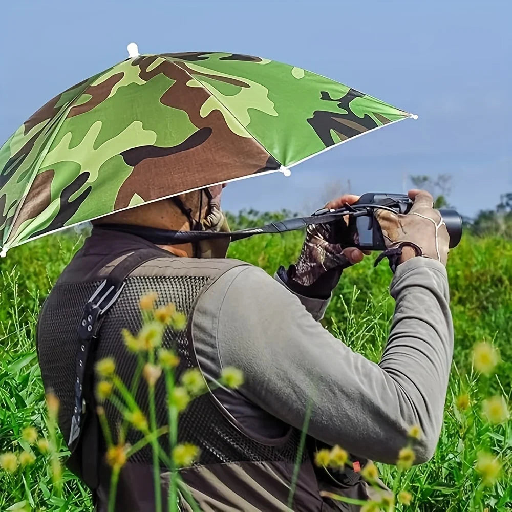 Une personne portant un chapeau parapluie camouflage prend une photo à l'extérieur dans un champ herbeux.