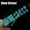 A hand holds a glow sticker featuring various icons and lines for a car window switch.