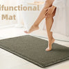 A dark green waffle weave bath mat is placed on a light wooden floor next to a white bathtub.