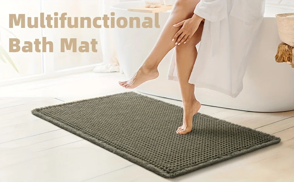 A dark green waffle weave bath mat is placed on a light wooden floor next to a white bathtub.