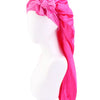 Pink satin sleep bonnet with a large bow draped over a white mannequin head.