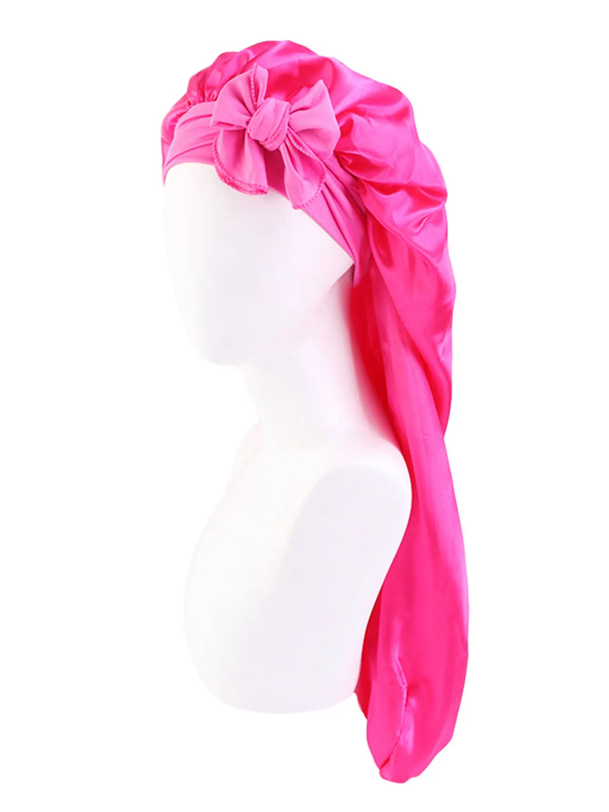Pink satin sleep bonnet with a large bow draped over a white mannequin head.