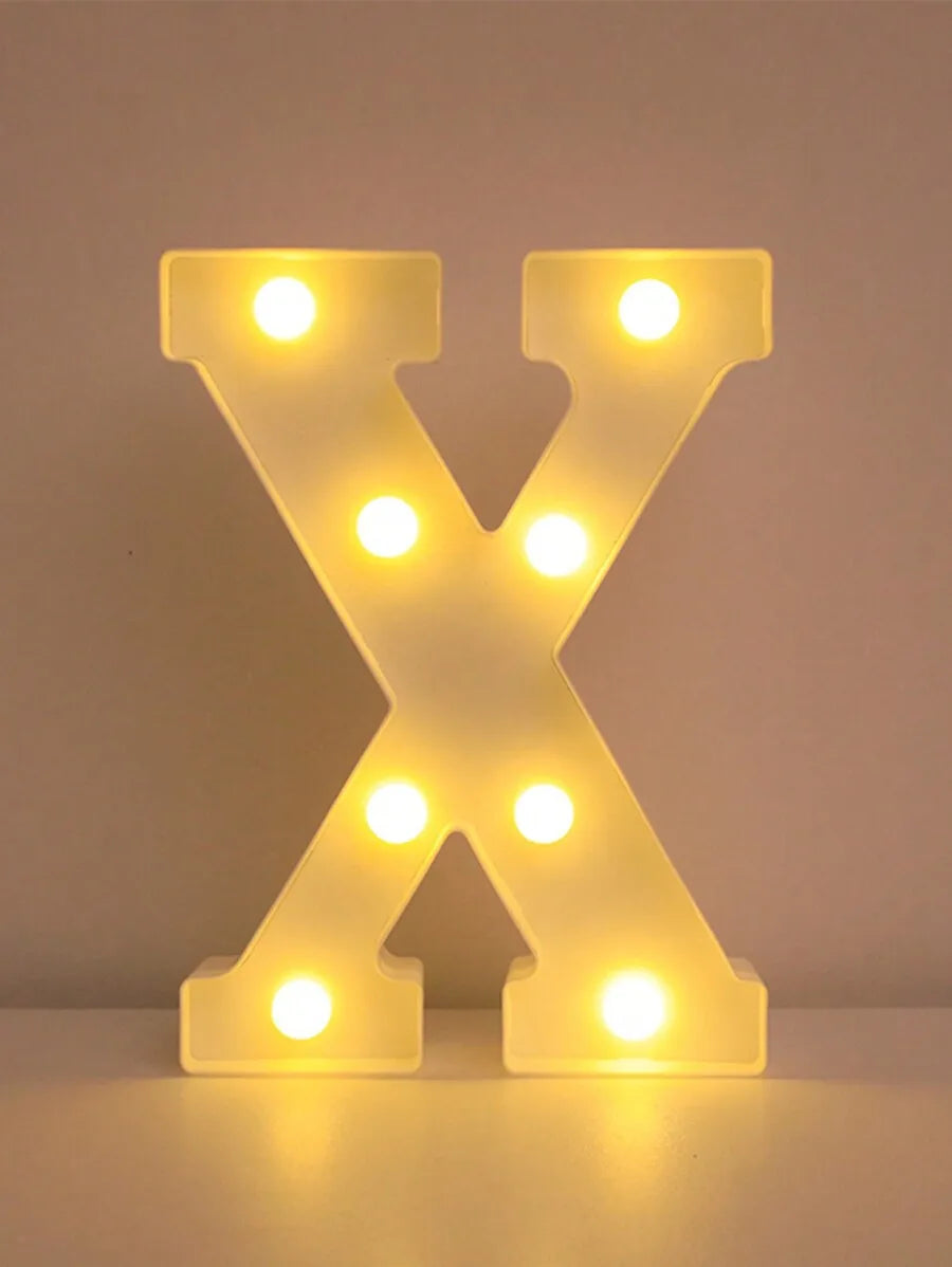 A glowing yellow LED letter night light shaped like the letter X, illuminating various points.