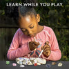 A young girl is excavating gemstones and crystals from a rock using a kit, learning while playing.